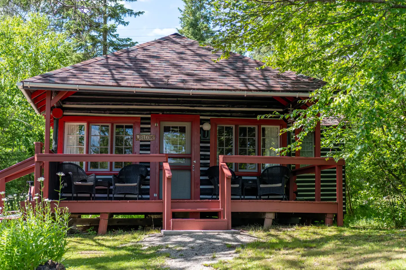 A large cabin with a deck facing the lake.